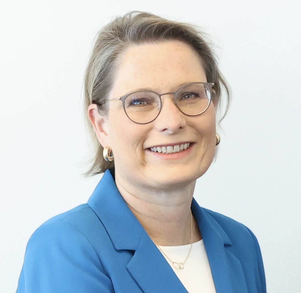 Official portrait of Dr. Stefanie Hubig smiling, wearing a blue blazer and glasses, against a light background.
