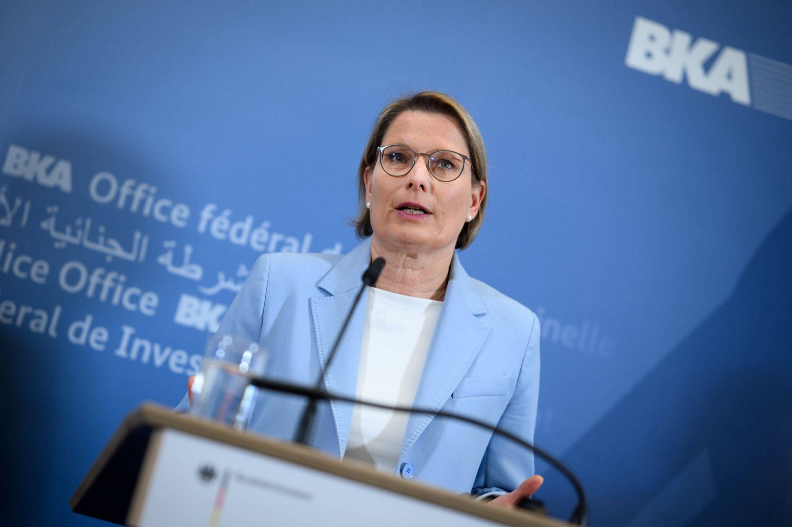 Stefanie Hubig speaking at a lectern in front of a blue backdrop of the Federal Criminal Police Office (BKA).