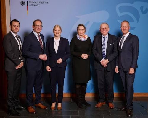 Group photo of six people, including Stefanie Hubig in a dark dress and scarf, in front of a Federal Ministry of the Interior backdrop.